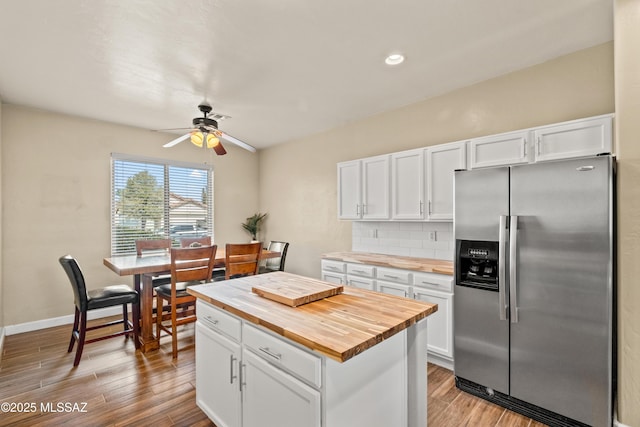 kitchen with light wood-type flooring, white cabinetry, wood counters, and stainless steel fridge with ice dispenser