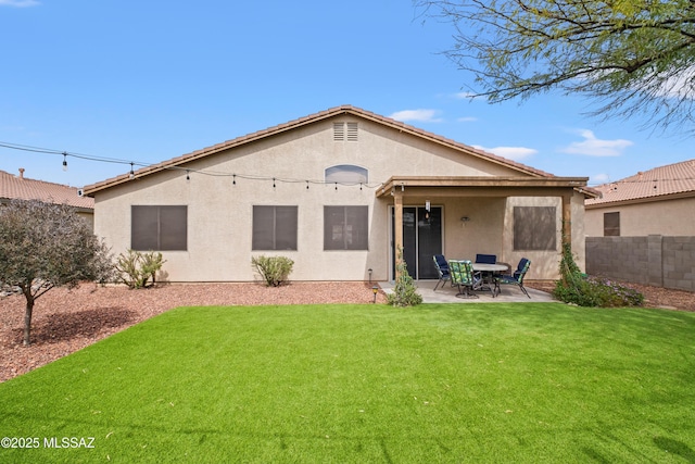 rear view of house with a yard, fence, a patio, and stucco siding