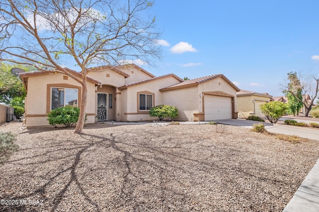 mediterranean / spanish-style house featuring a garage, concrete driveway, a tiled roof, and stucco siding