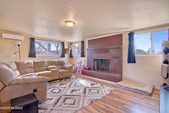 living room featuring a wall mounted AC, a fireplace, and wood finished floors