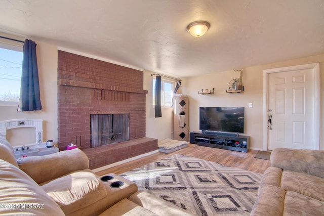 living area with a brick fireplace and wood finished floors