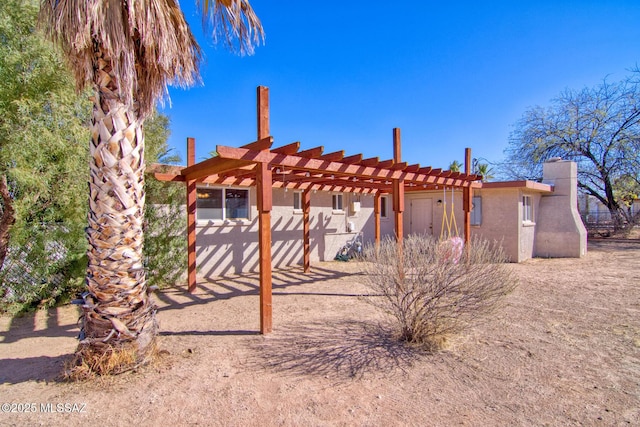 rear view of property featuring stucco siding and a pergola