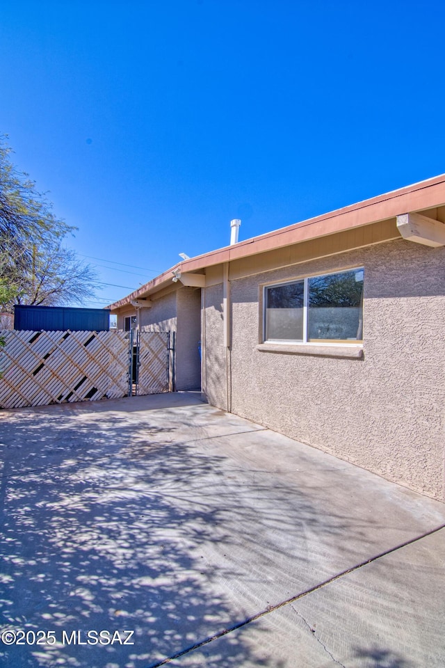 exterior space with a gate and stucco siding