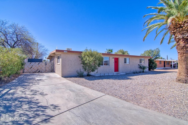 ranch-style home with a gate and stucco siding