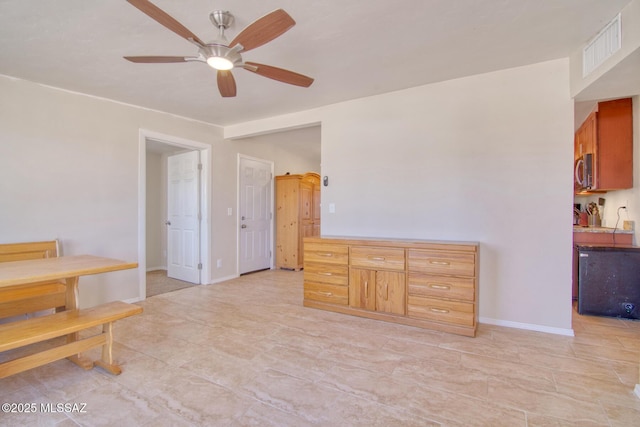 interior space with ceiling fan, visible vents, and baseboards