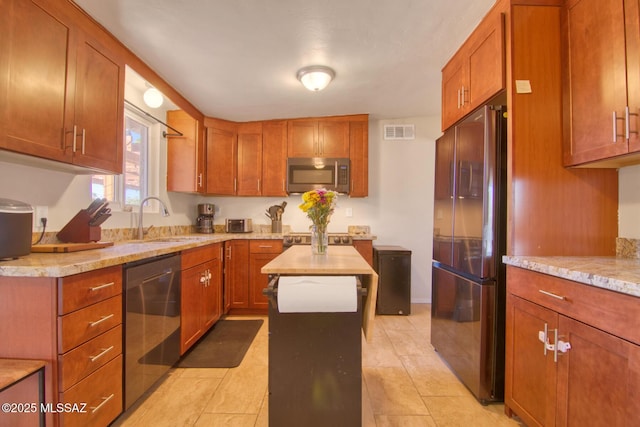 kitchen featuring appliances with stainless steel finishes, brown cabinetry, a sink, and visible vents