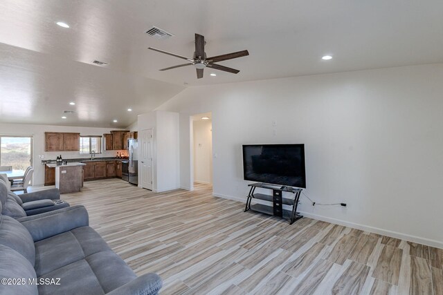 living area with light wood finished floors, lofted ceiling, recessed lighting, visible vents, and baseboards