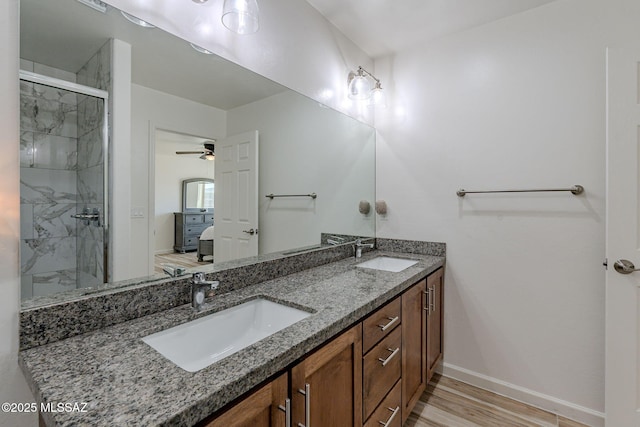 bathroom with a marble finish shower, connected bathroom, a sink, and wood finished floors