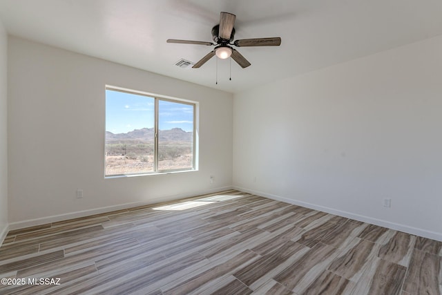 empty room with light wood-style flooring, visible vents, ceiling fan, and baseboards