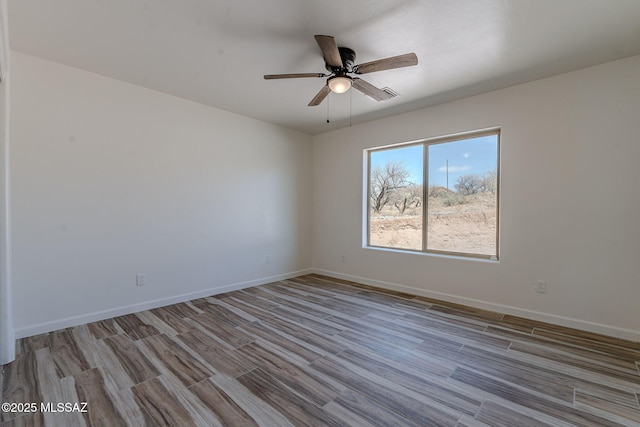 empty room with a ceiling fan, baseboards, and wood finished floors