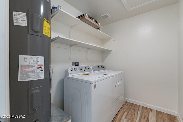 washroom featuring laundry area, baseboards, light wood-style flooring, independent washer and dryer, and heating unit