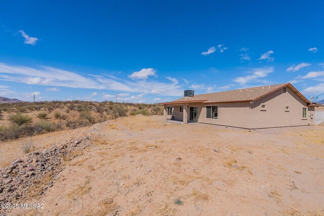 back of house with central air condition unit and stucco siding