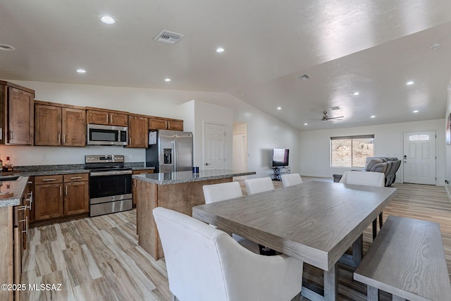 kitchen with a center island, stainless steel appliances, visible vents, vaulted ceiling, and light wood-type flooring