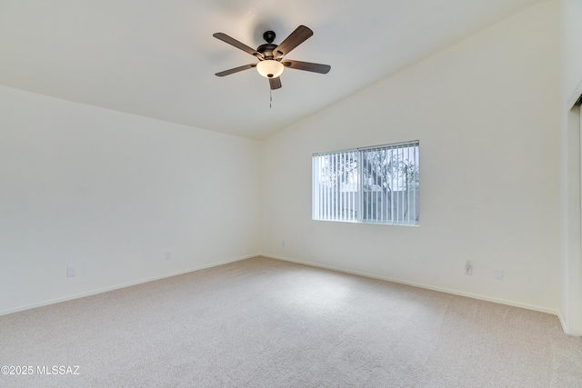 empty room featuring lofted ceiling, light colored carpet, baseboards, and ceiling fan