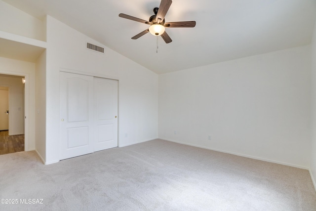 unfurnished bedroom with visible vents, baseboards, light colored carpet, lofted ceiling, and a closet