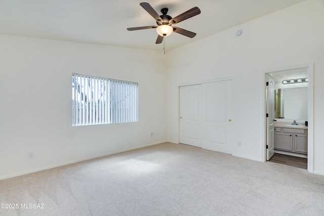 unfurnished bedroom with ensuite bathroom, a sink, a closet, carpet, and baseboards