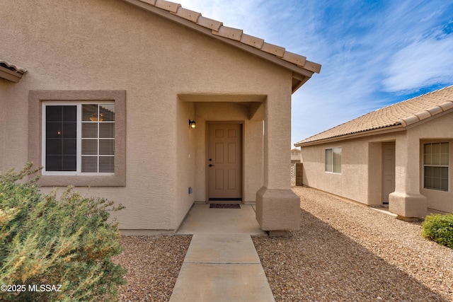 doorway to property with stucco siding and a tiled roof