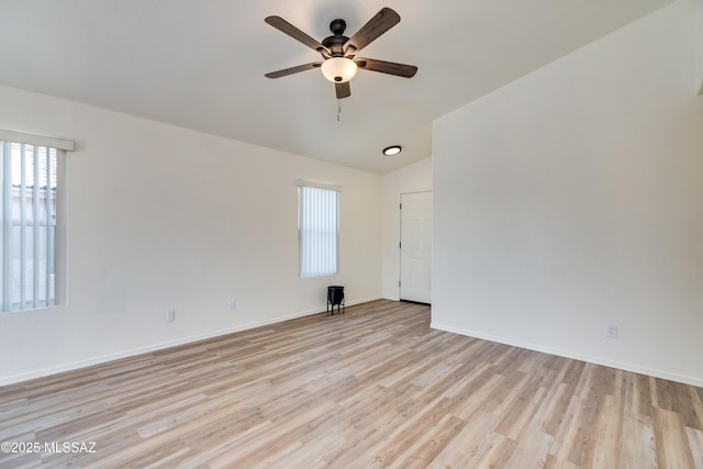 empty room featuring a ceiling fan, vaulted ceiling, light wood-style floors, and baseboards