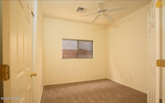 carpeted empty room with baseboards, visible vents, and a ceiling fan