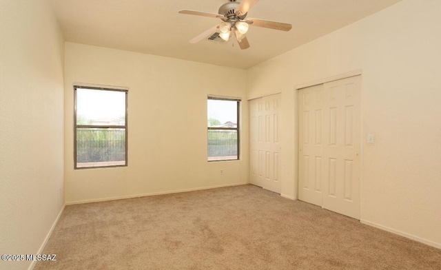 unfurnished bedroom featuring carpet, two closets, visible vents, a ceiling fan, and baseboards