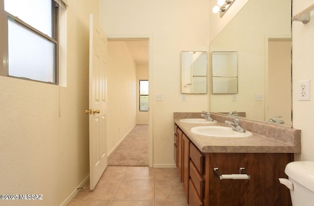 full bath featuring double vanity, a sink, toilet, and tile patterned floors