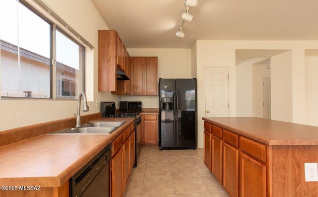 kitchen with light tile patterned floors, black appliances, brown cabinetry, and a sink