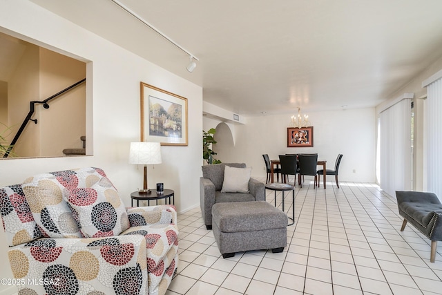 living room featuring stairway, light tile patterned flooring, rail lighting, and a notable chandelier