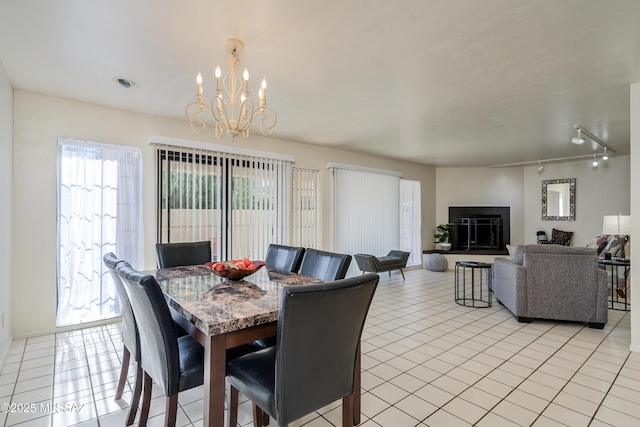 dining area featuring light tile patterned floors, a fireplace, a chandelier, and rail lighting