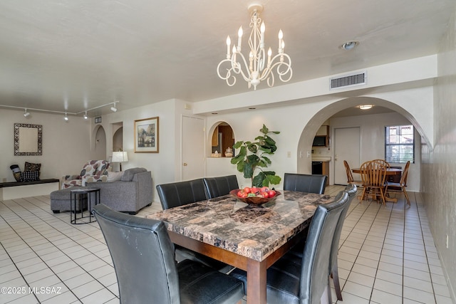 dining space featuring light tile patterned floors, visible vents, arched walkways, and track lighting