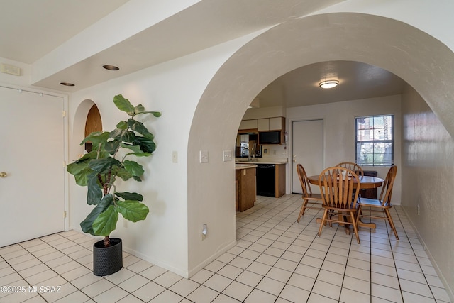 dining space with light tile patterned floors, arched walkways, and baseboards