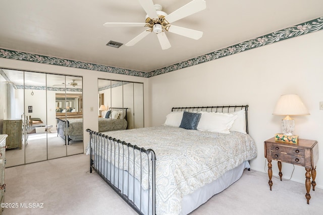 carpeted bedroom with ceiling fan, visible vents, and multiple closets