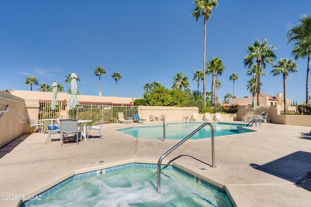 community pool featuring a patio area, a hot tub, and fence