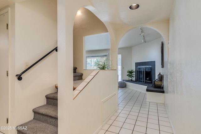 staircase featuring tile patterned flooring, a fireplace, and track lighting