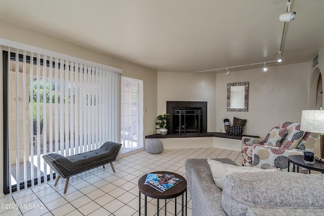 living area featuring rail lighting, visible vents, a fireplace, and tile patterned floors