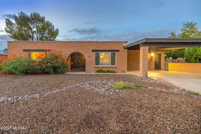 view of front of house with an attached carport, concrete driveway, and brick siding