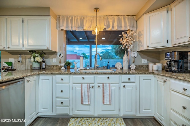 kitchen with light stone counters, white cabinets, a sink, and stainless steel dishwasher