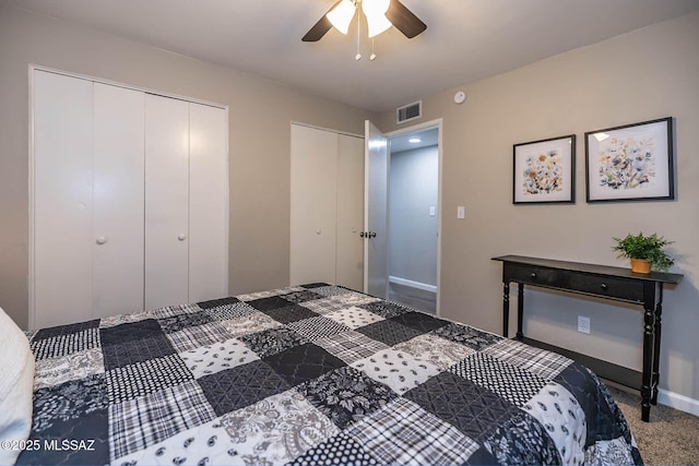 bedroom featuring carpet, two closets, visible vents, a ceiling fan, and baseboards