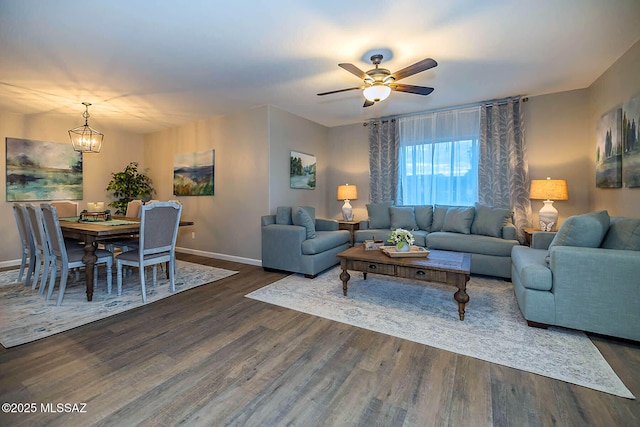 living area featuring dark wood finished floors, baseboards, and ceiling fan with notable chandelier