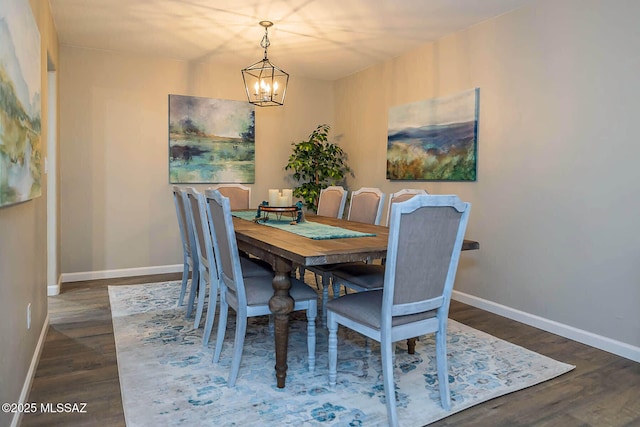 dining space featuring baseboards, wood finished floors, and a notable chandelier