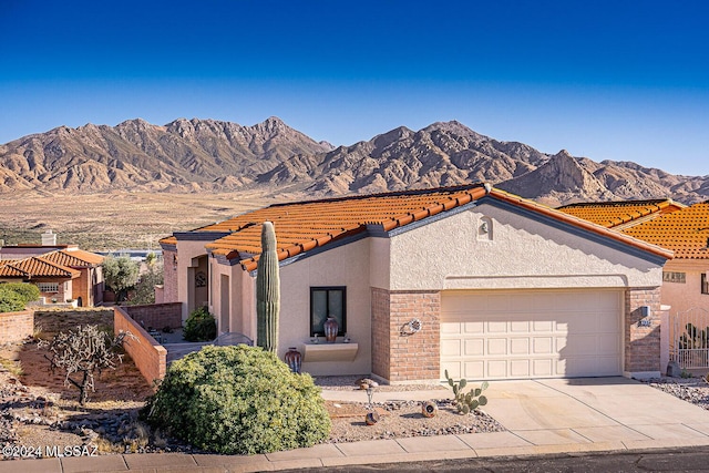 view of front of house featuring stucco siding, concrete driveway, a mountain view, a garage, and a tiled roof