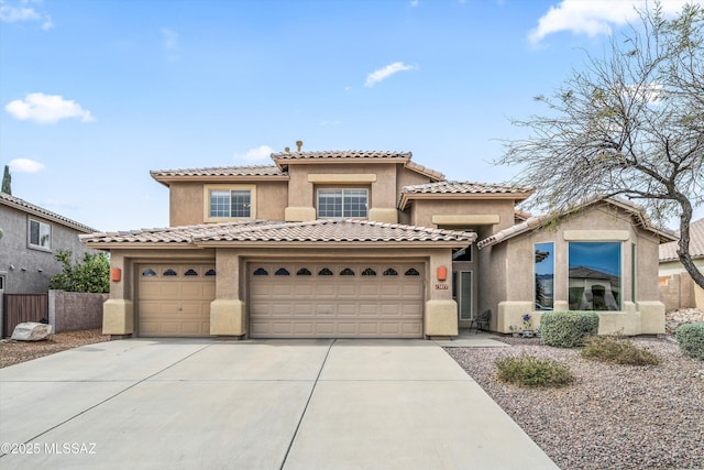 mediterranean / spanish home featuring driveway, a garage, a tiled roof, fence, and stucco siding