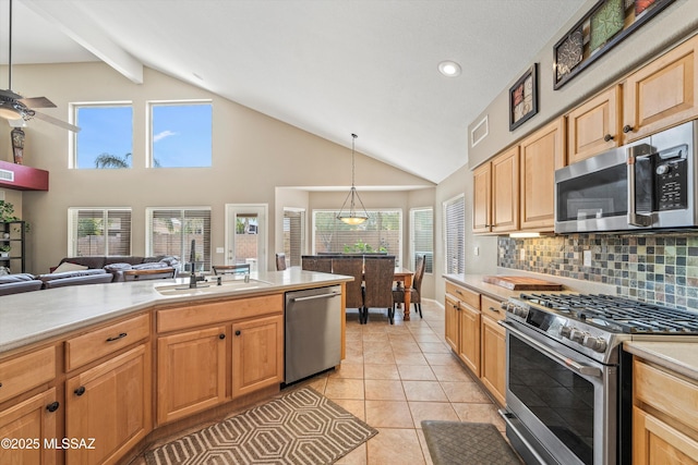 kitchen featuring lofted ceiling, light countertops, appliances with stainless steel finishes, and a sink