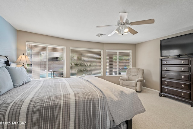 carpeted bedroom featuring baseboards, multiple windows, visible vents, and a ceiling fan