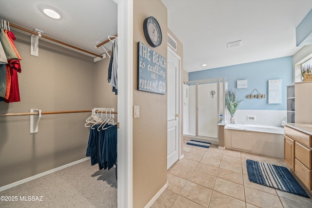 full bath featuring a spacious closet, a shower stall, a bath, baseboards, and tile patterned floors