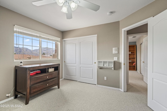 bedroom featuring light carpet, a ceiling fan, baseboards, and a closet