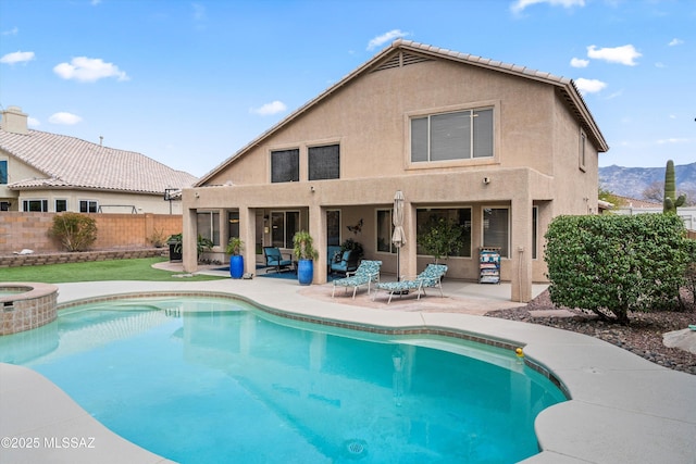 view of swimming pool with a pool with connected hot tub, a patio, and fence