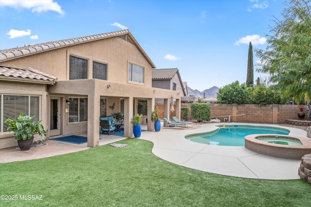 view of pool with a patio, a lawn, fence, and a pool with connected hot tub