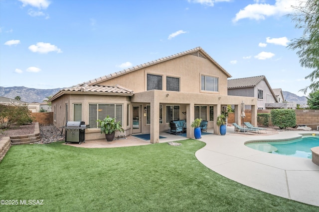 back of property with a lawn, a patio, a fenced backyard, a mountain view, and stucco siding