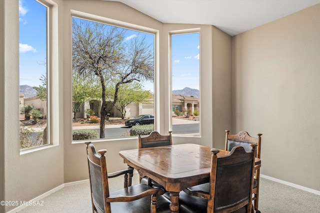 carpeted dining space with plenty of natural light, baseboards, and a mountain view