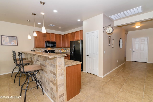 kitchen with decorative backsplash, a breakfast bar, decorative light fixtures, a peninsula, and black appliances